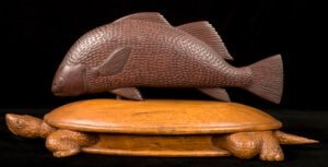Wooden sculpture of a fish atop a turtle
